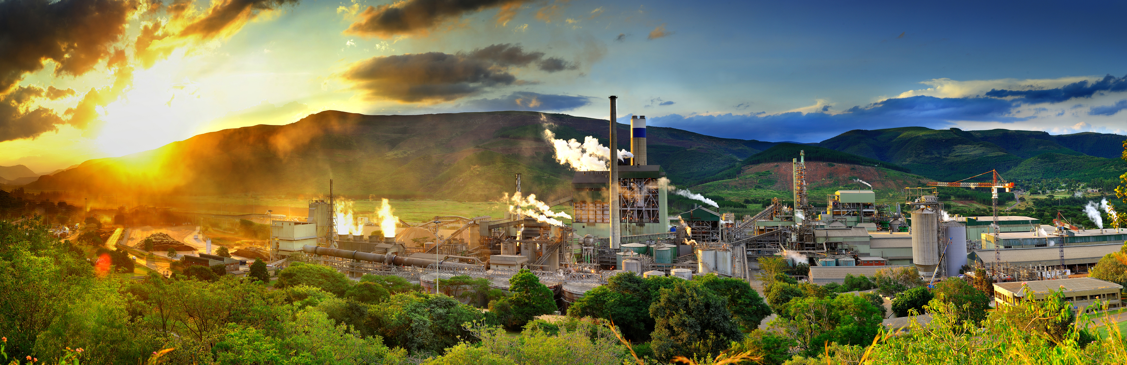 factories surrounded by mountains at sunset