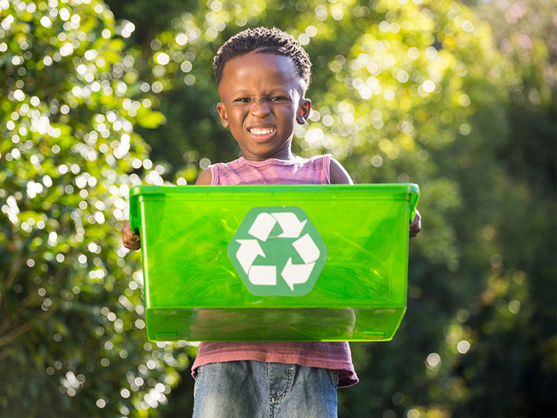 African child holding up green recycling box