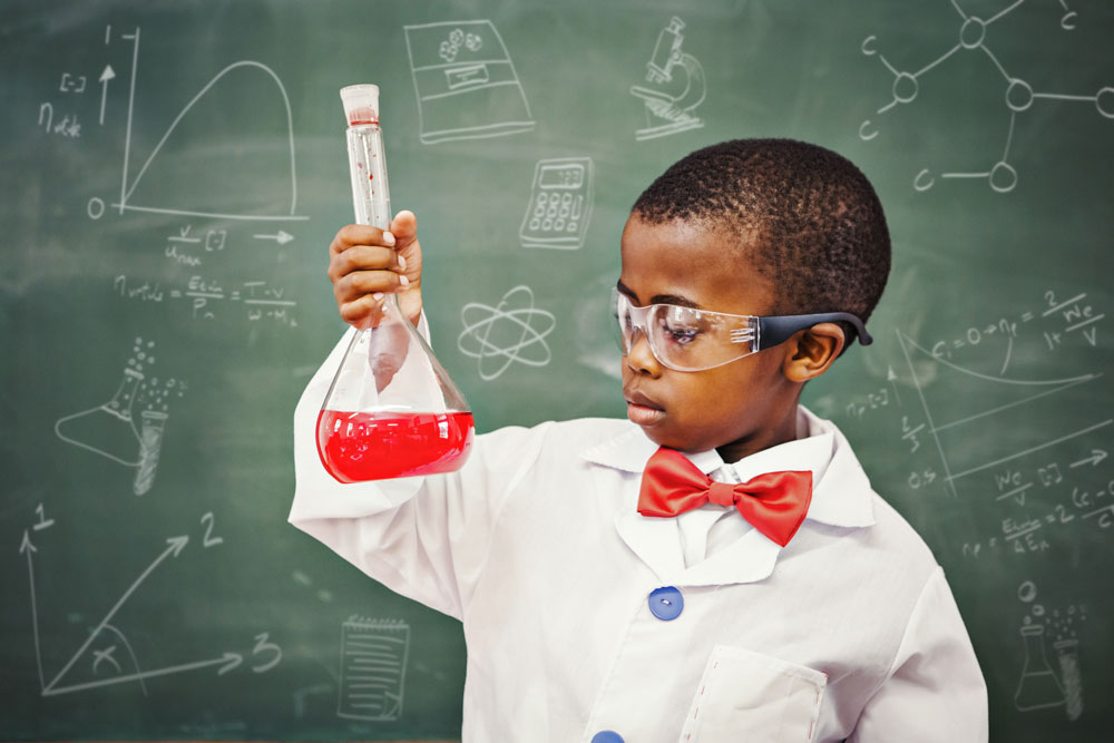 Young boy holding up test tube in science classroom